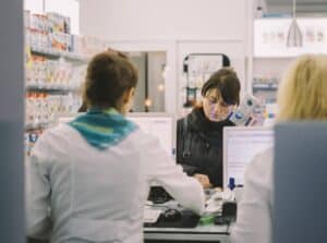 Woman at the Pharmacy counter with two pharmacists in the background